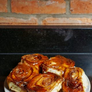 sticky buns on a plate against a red brick wall