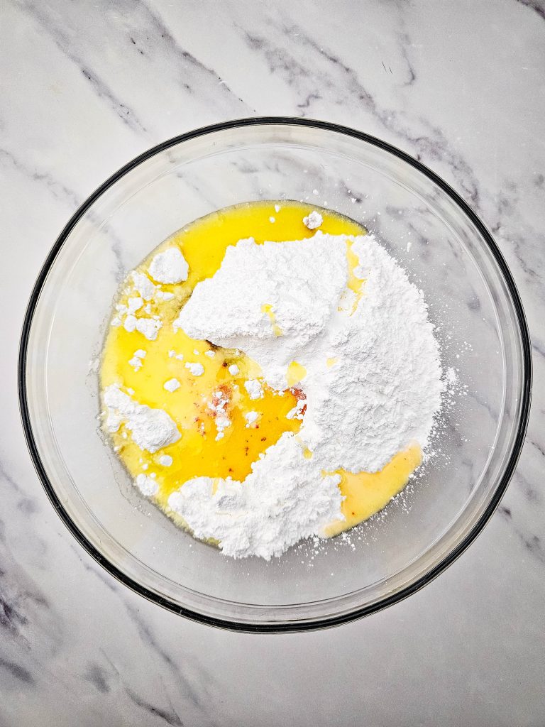 Butter and dry ingredients starting to combine in a glass bowl.
