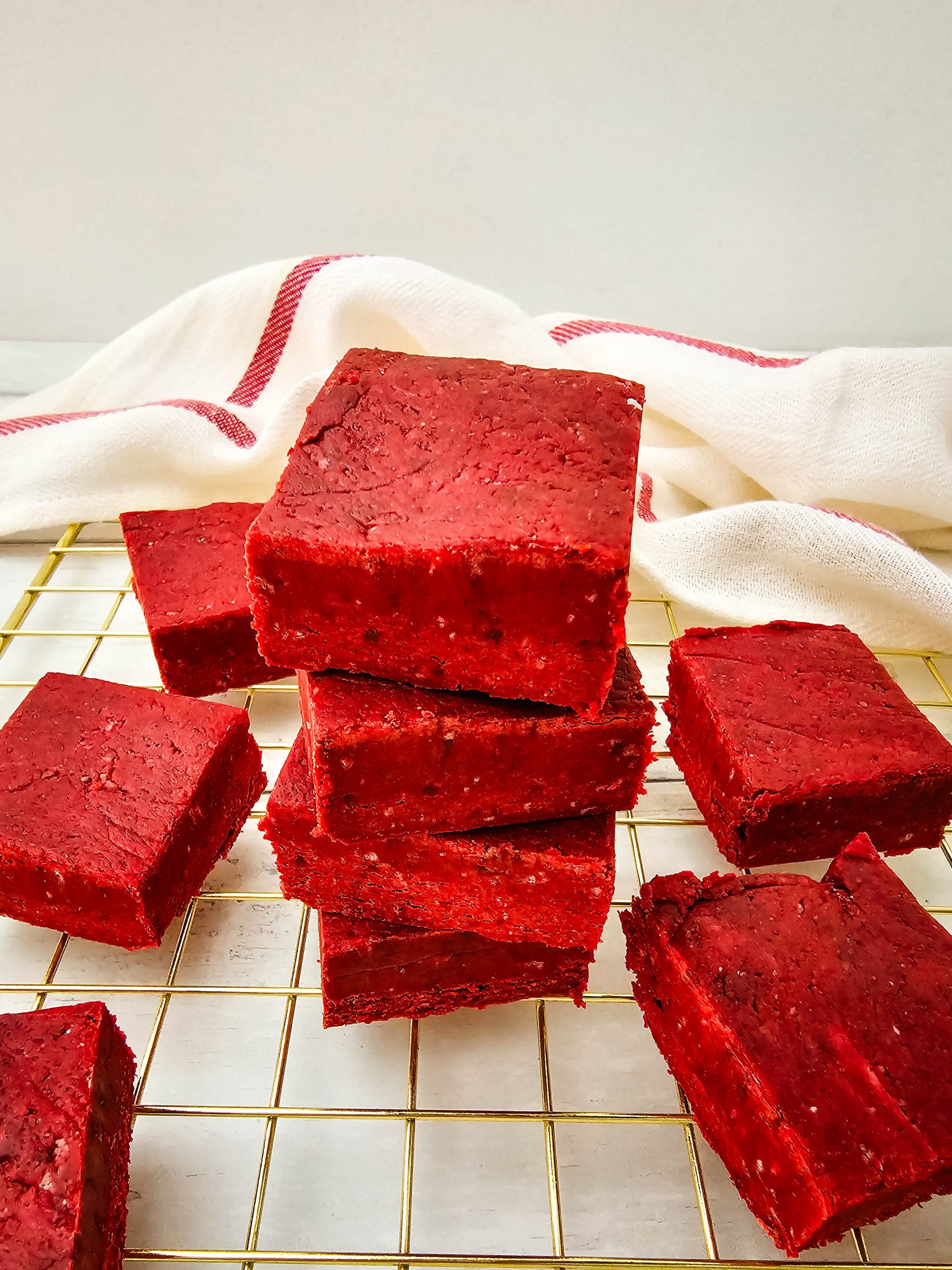 Stack of red velvet fudge squares on a wire rack.