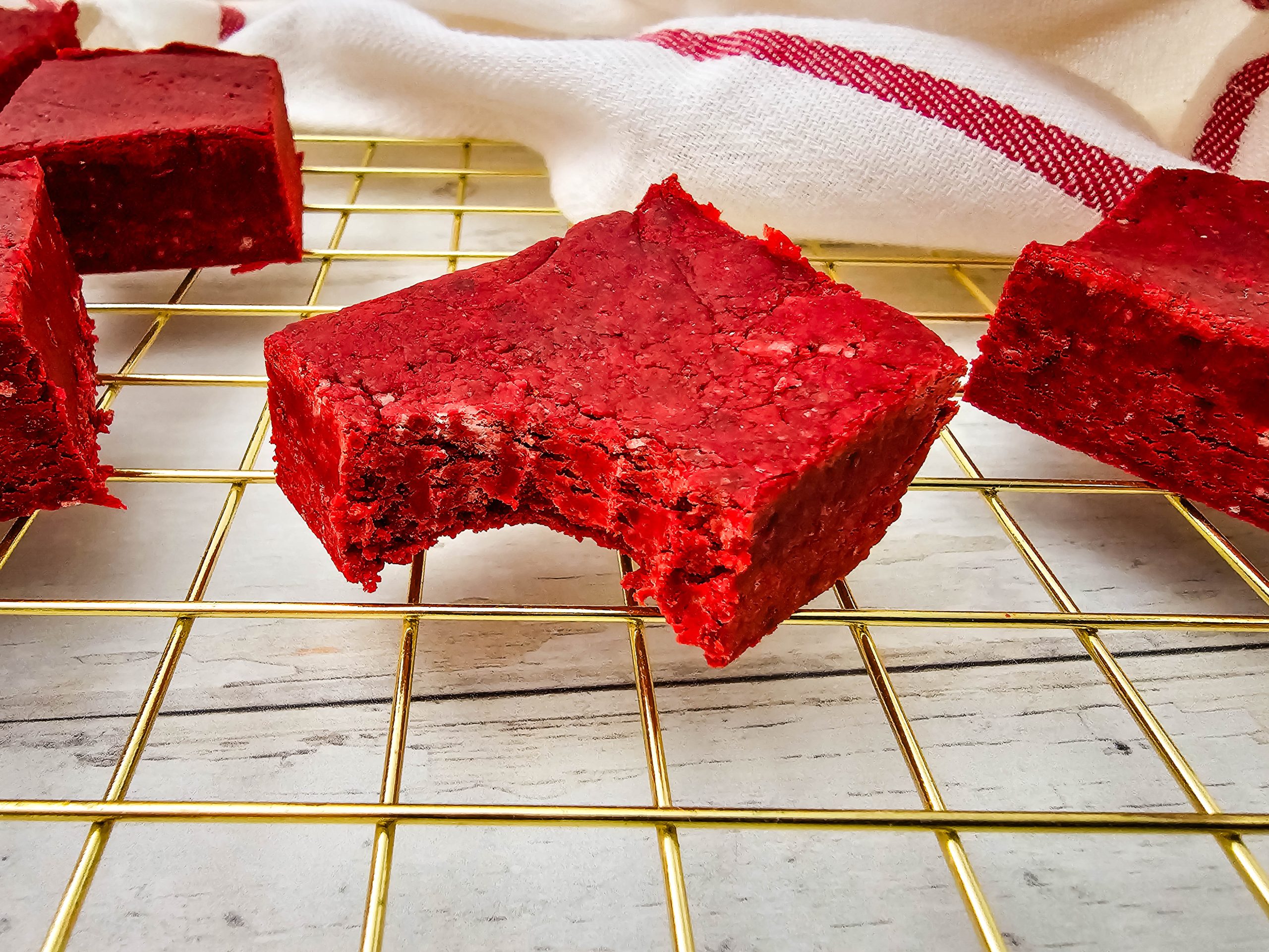 Stacked red velvet fudge pieces with smooth tops.