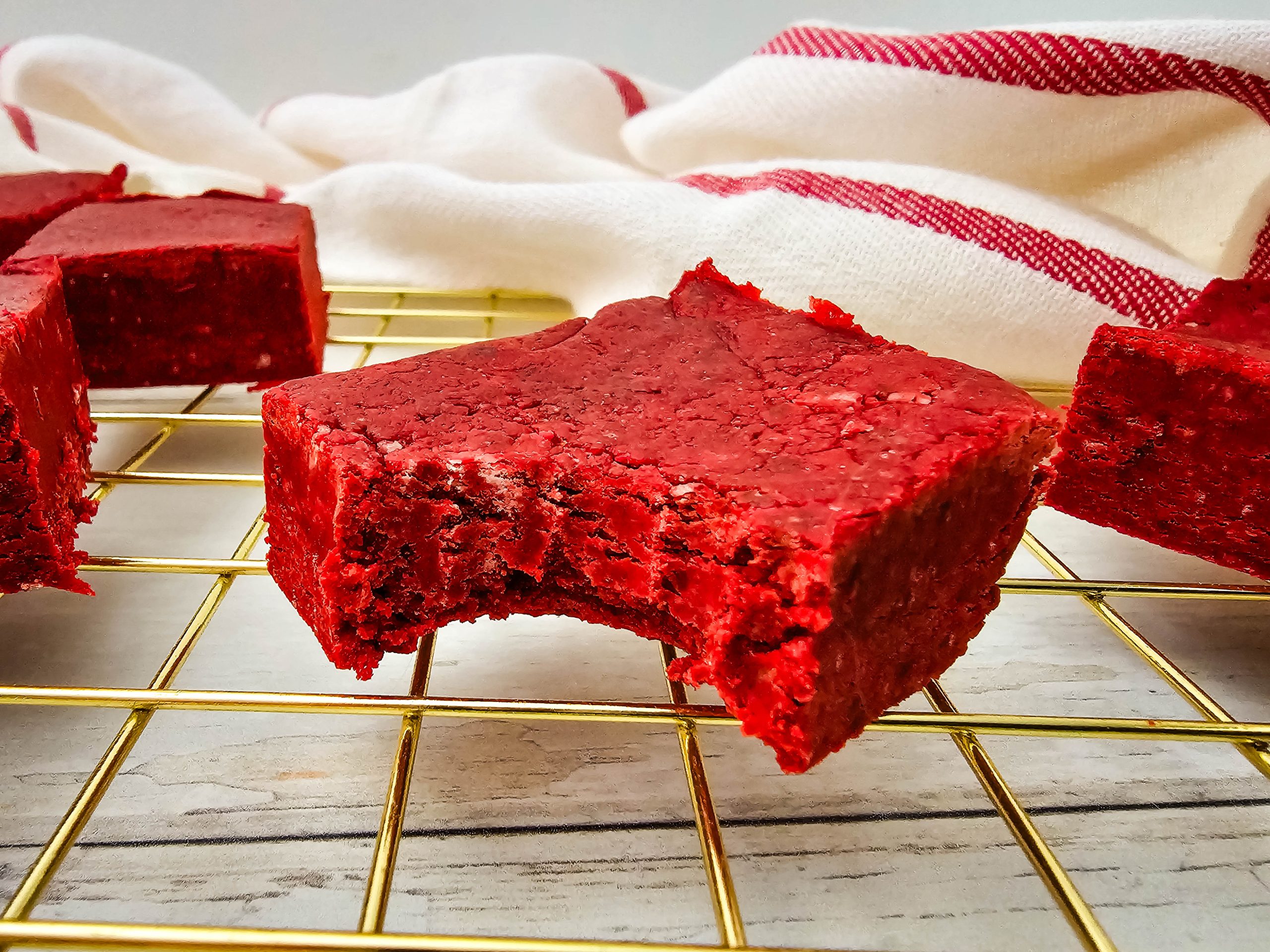 Red velvet fudge square with a bite taken out on a wire rack.