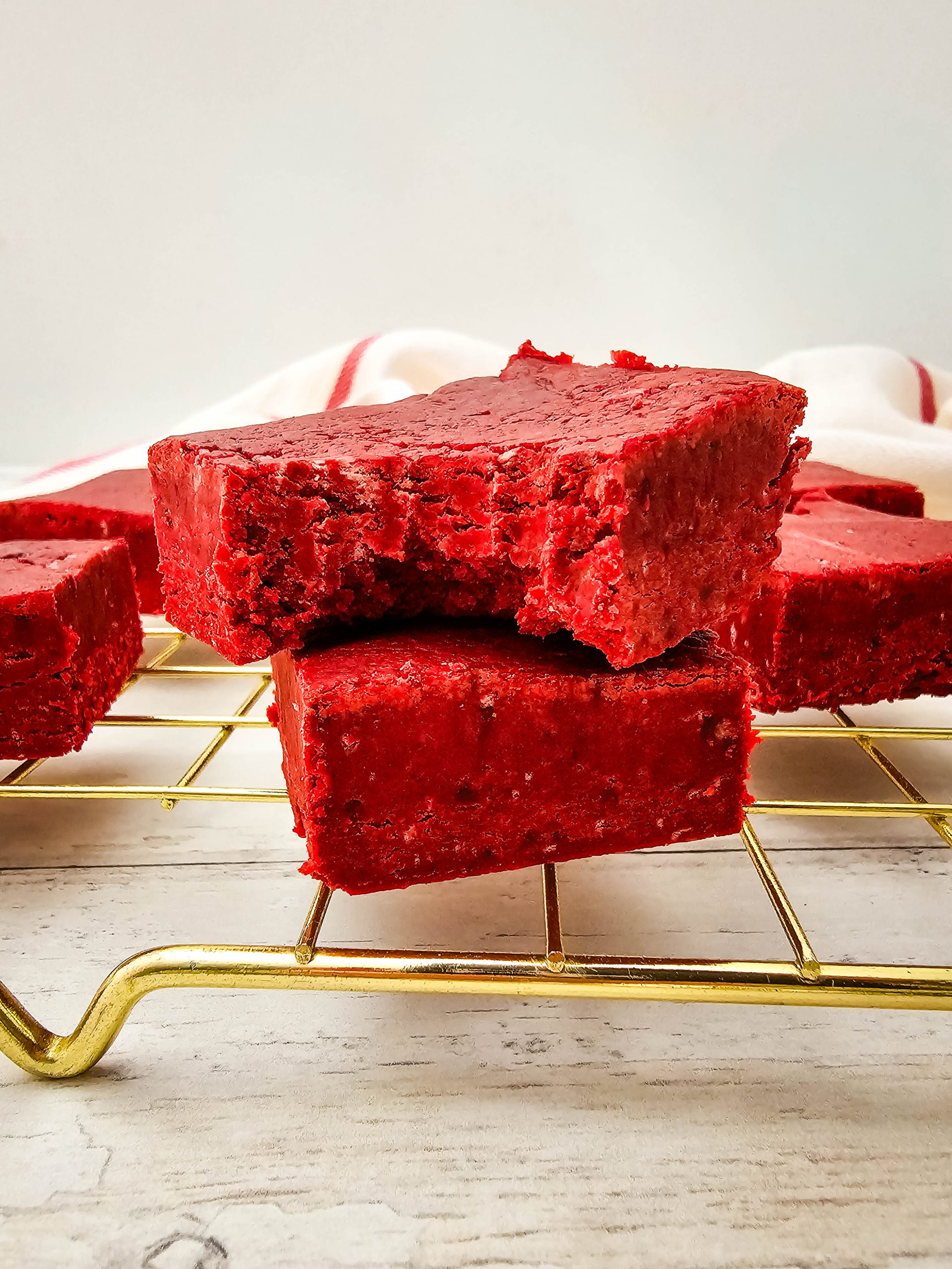 Red velvet fudge square stacked on another piece with bite visible.