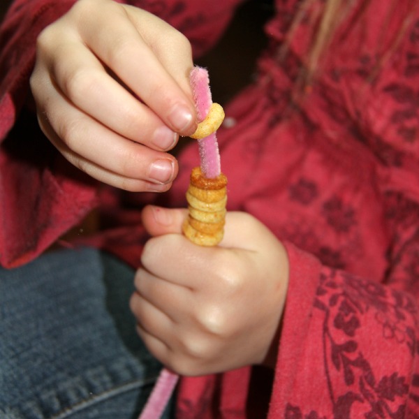 add the cereal on the pipe cleaner for this Valentine's Day craft for preschoolers
