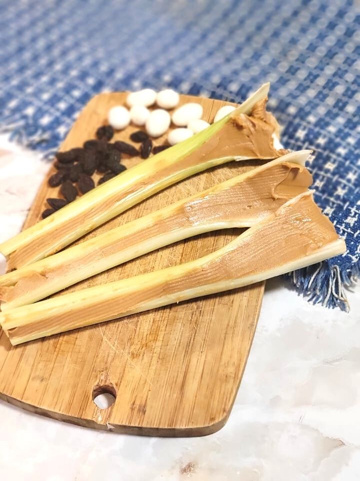 peanut butter filled celery on a brown cutting board