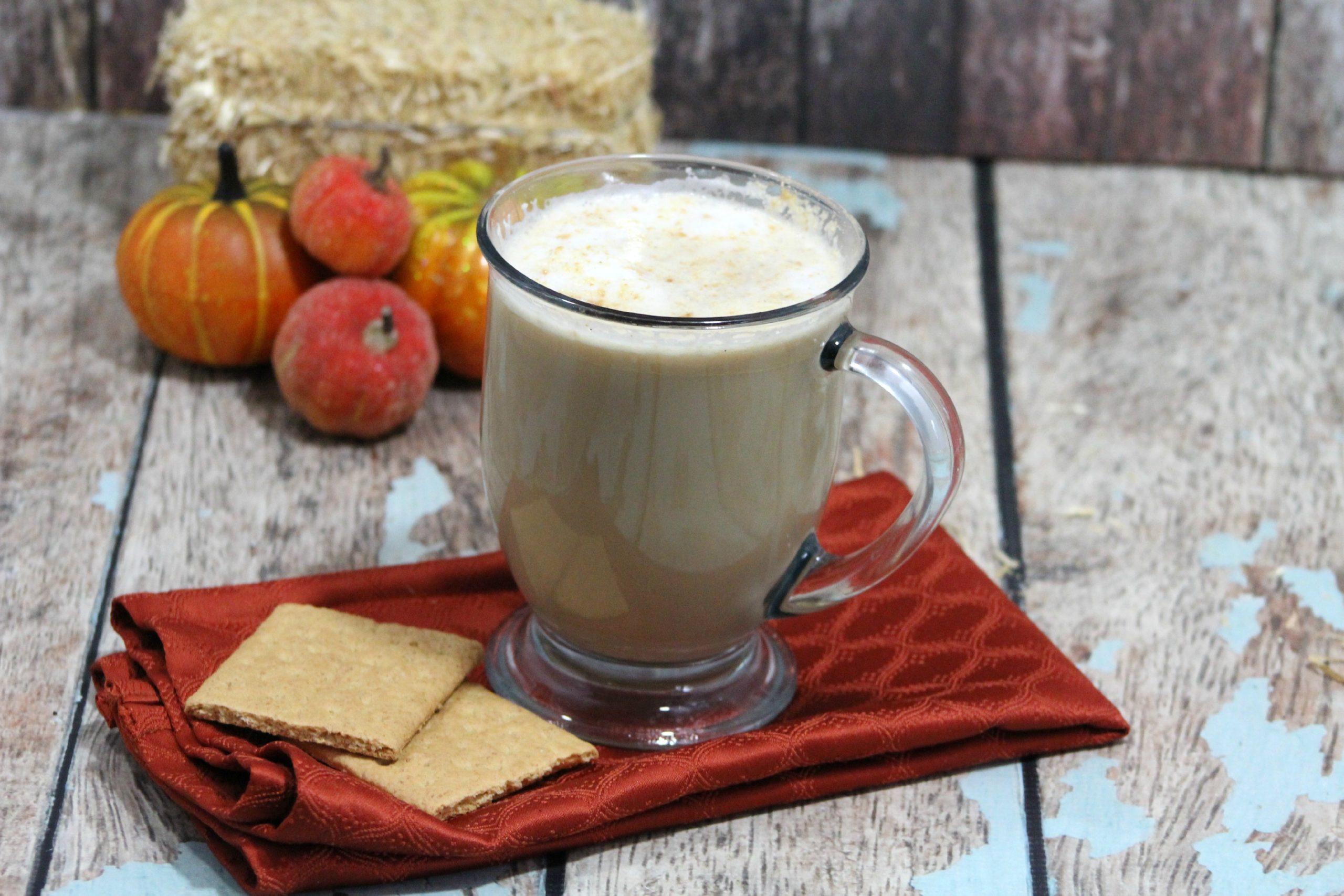Copycat Starbucks Graham Cracker Latte topped with frothy milk and crushed graham crackers in a white mug on a wooden table.