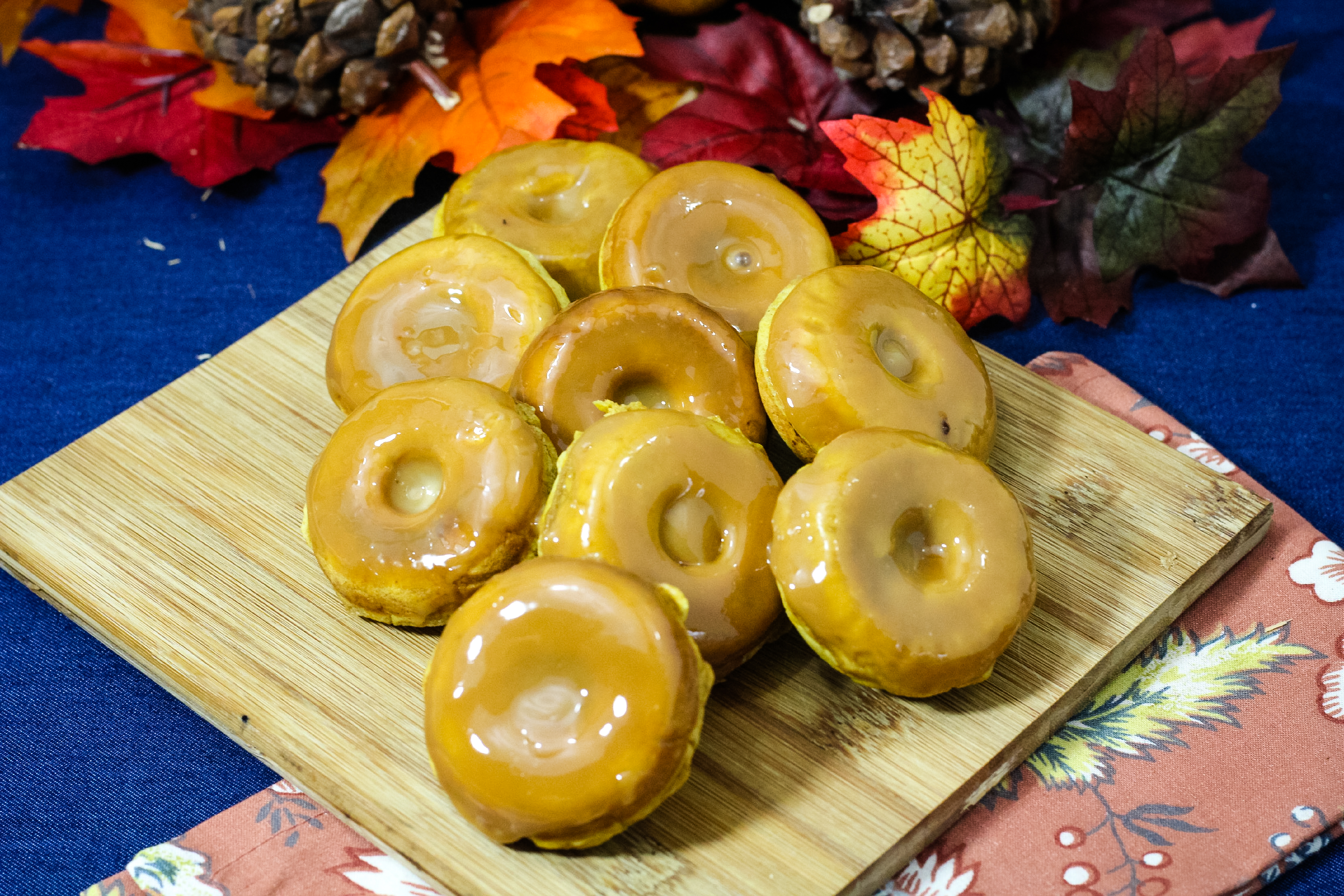 pumpkin spice donuts on a cutting board with a blue background