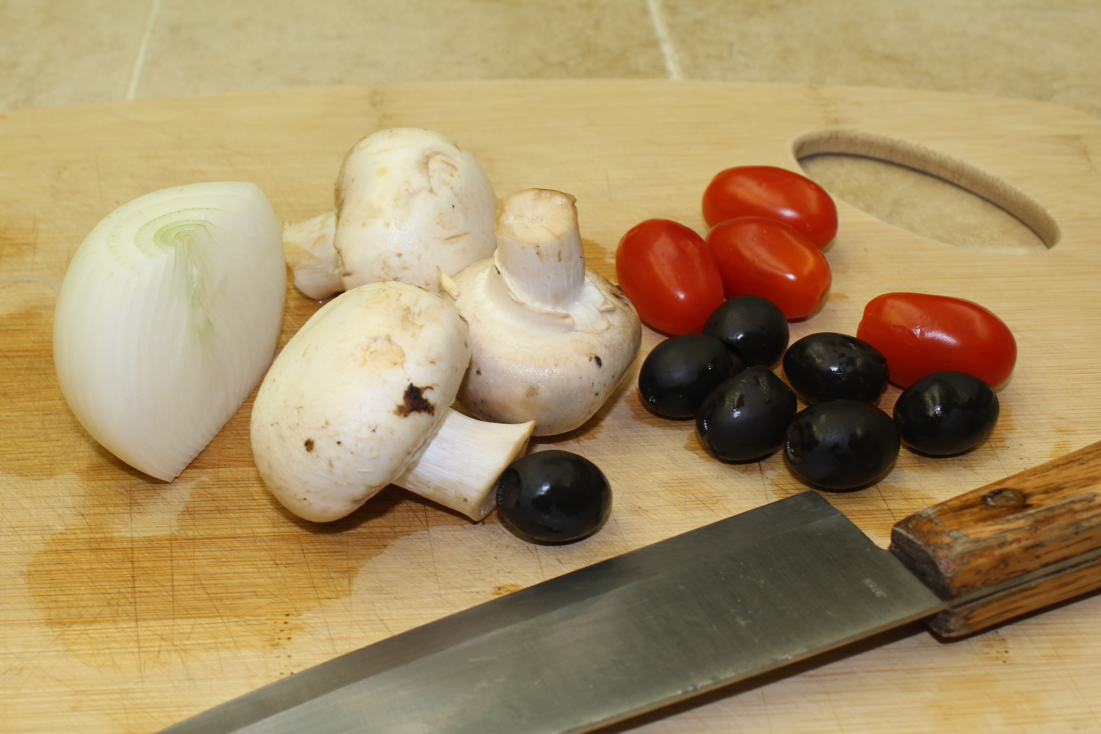 mushrooms, olives and tomatoes on olives on a cutting board