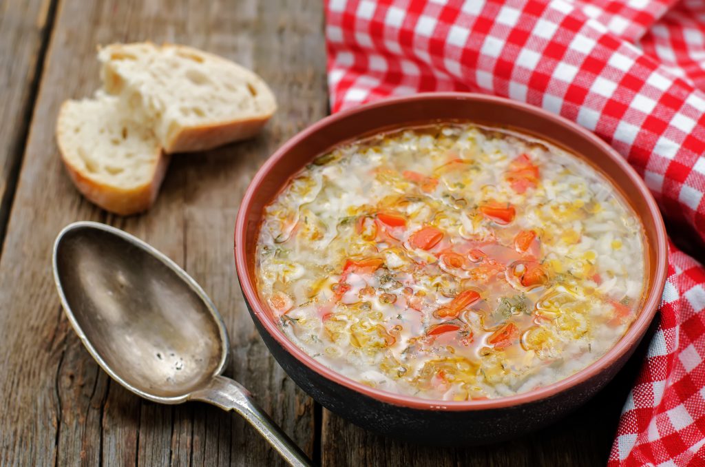 turkey and rice soup on a wood background with a checkered napkin