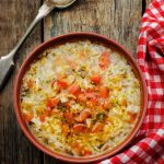 turkey and rice soup on a wood background with a checkered napkin