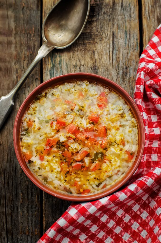 turkey and rice soup on a wood background with a checkered napkin