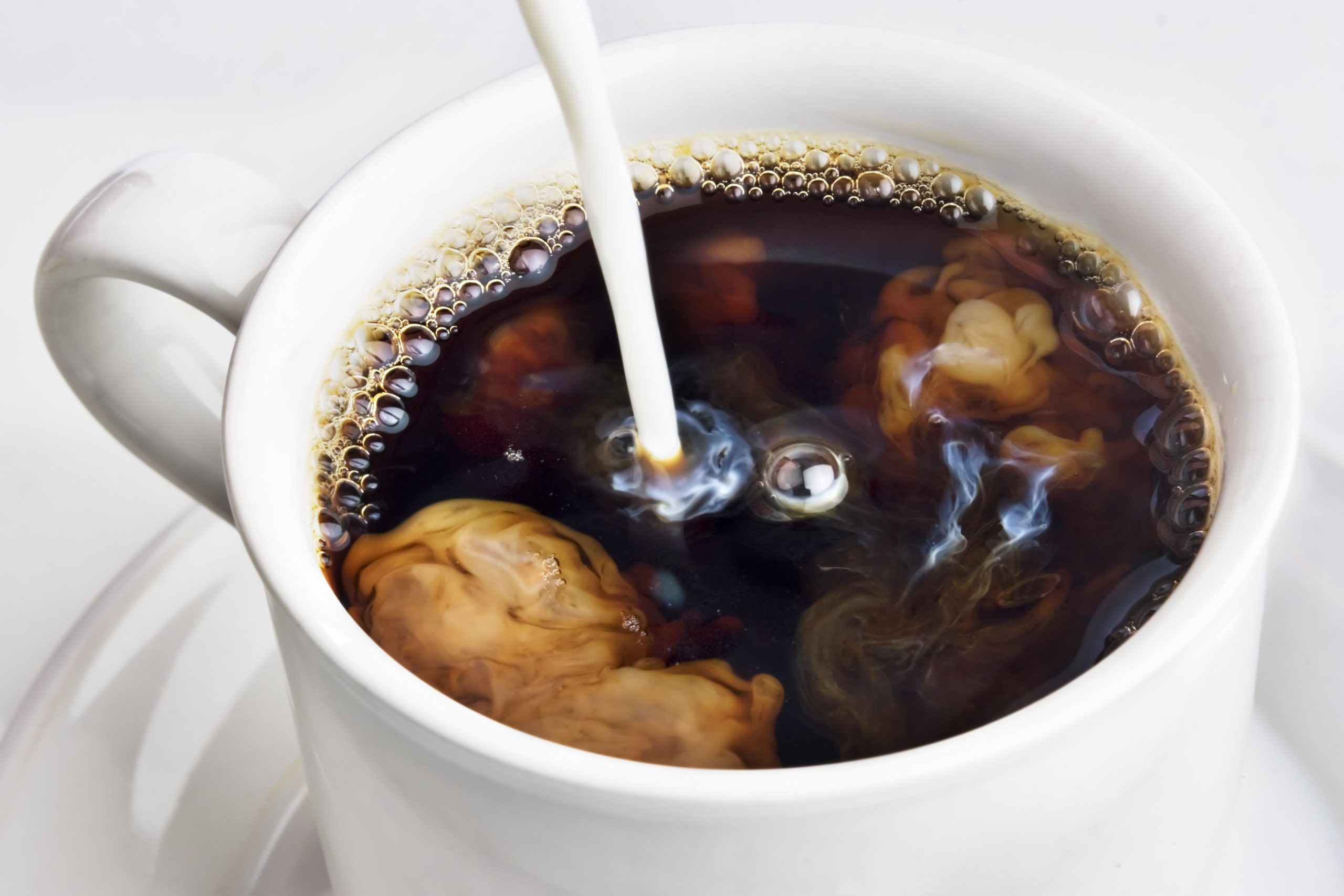 creamer being poured into coffe