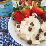healthy fruit dip on a blue mat with rx nut butter next to it with strawberries in the bowl