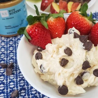 healthy fruit dip on a blue mat with rx nut butter next to it with strawberries in the bowl