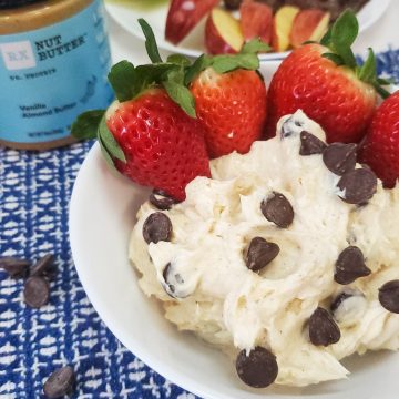 healthy fruit dip on a blue mat with rx nut butter next to it with strawberries in the bowl