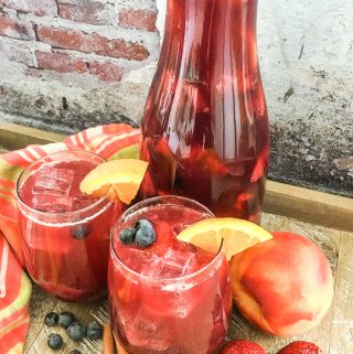 Sparkling Berry Peach Sangria in a pitcher and glasses with fresh fruit