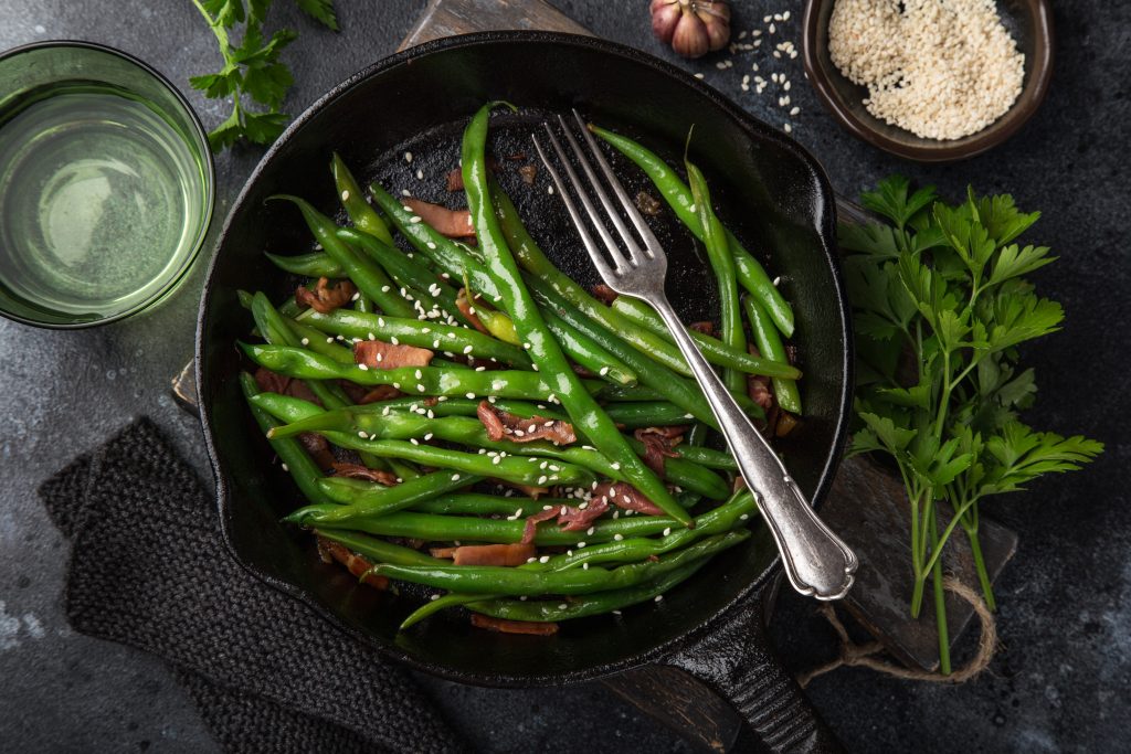 green beans and bacon in a skillet with a fork