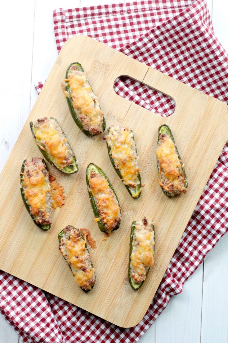 Stuffed Jalapeno Poppers with bacon and turkey on a wooden serving board and on a red checkered napkin