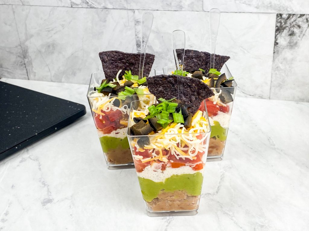 7 layer dip cups together on a white tray