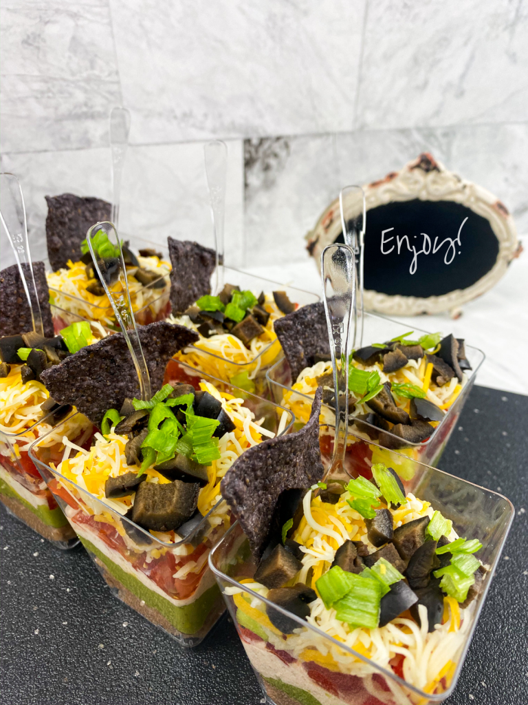 7 layer dip cups together on a gray tray