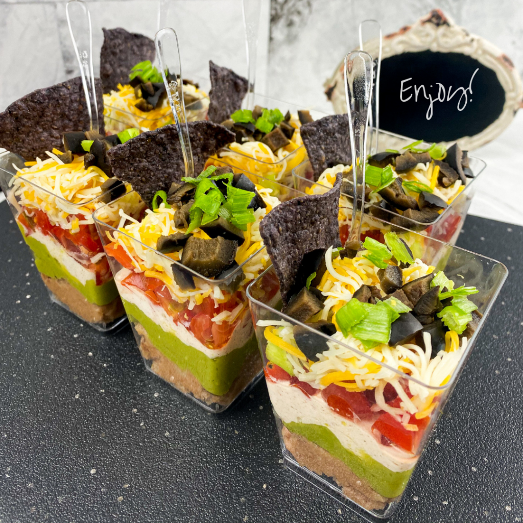 7 layer dip cups together on a gray tray