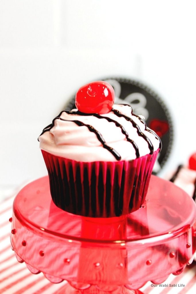 Chocolate Cherry Cupcakes with a red paper liner sitting on a red cake stand