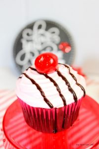 Chocolate cupcakes covered in cherry frosting and topped with a cherry.