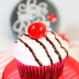 Chocolate cupcakes covered in cherry frosting and topped with a cherry.