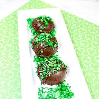 Hot Chocolate Bombs decorated with green sprinkles and on a white tray
