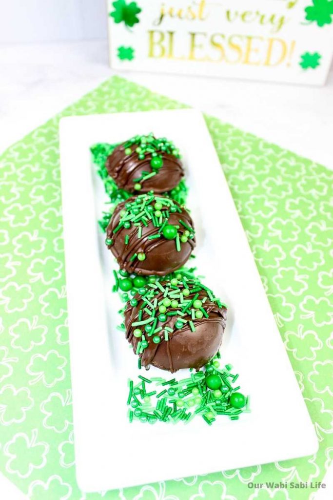 Hot Chocolate Bombs decorated with green sprinkles and on a white tray