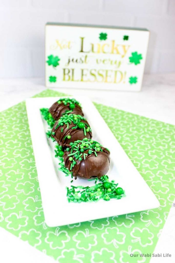 St Patrick's Day Hot Chocolate Bombs on a white tray with green sprinkles
