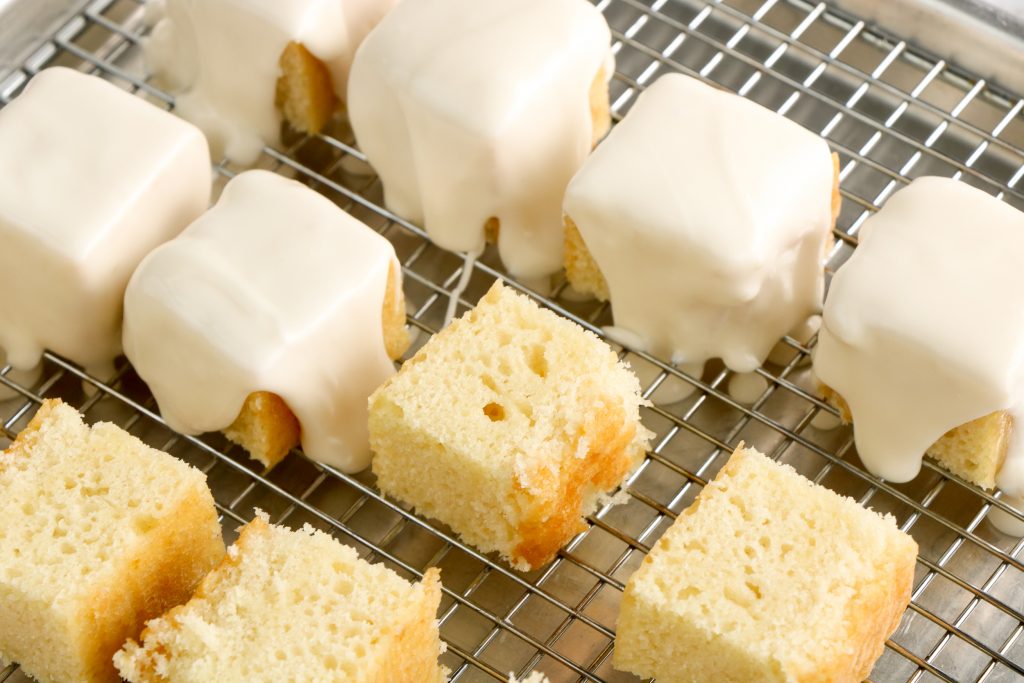 Cake squares with frosting being poured over the squares