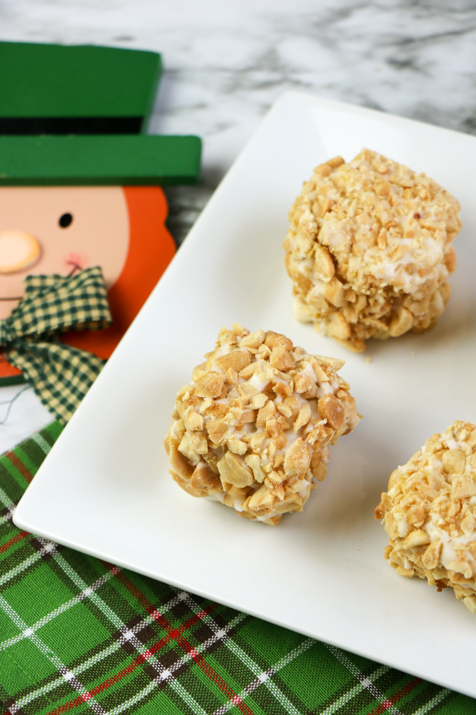 Blarney Stone Squares covered in peanuts and vanilla glaze on a white plate
