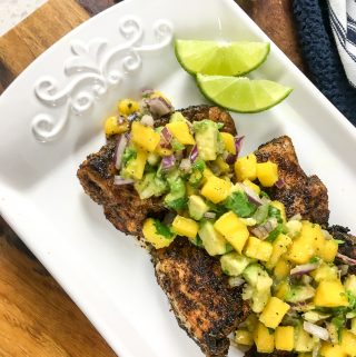 Four pieces of snapper seasoned with Cajun seasoning on a white tray and topped with salsa