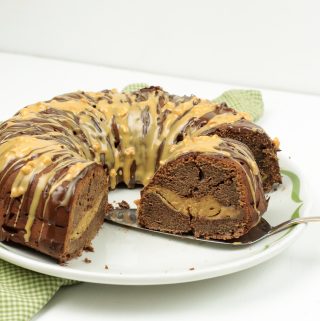 Chocolate Peanut Butter Bundt Cake full of peanut butter fluff and drizzled with chocolate and peanut butter on a white plate.