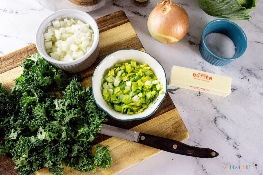 Chopped kale, onions, and leeks on a wooden cutting board