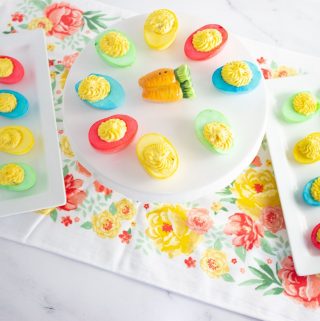 Two White trays and a cake stand full of brightly colored deviled eggs