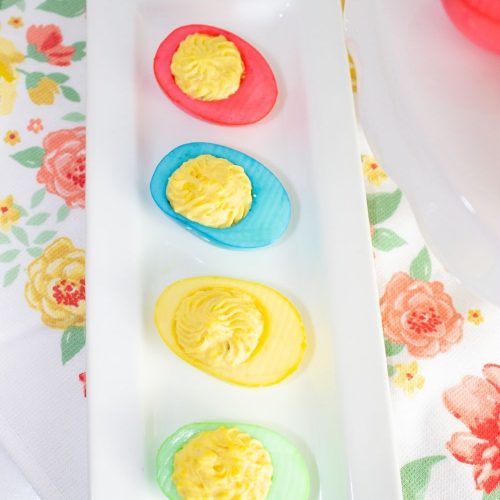 Brightly colored deviled eggs for Easter on a white tray