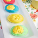 Brightly colored deviled eggs for Easter on a white tray