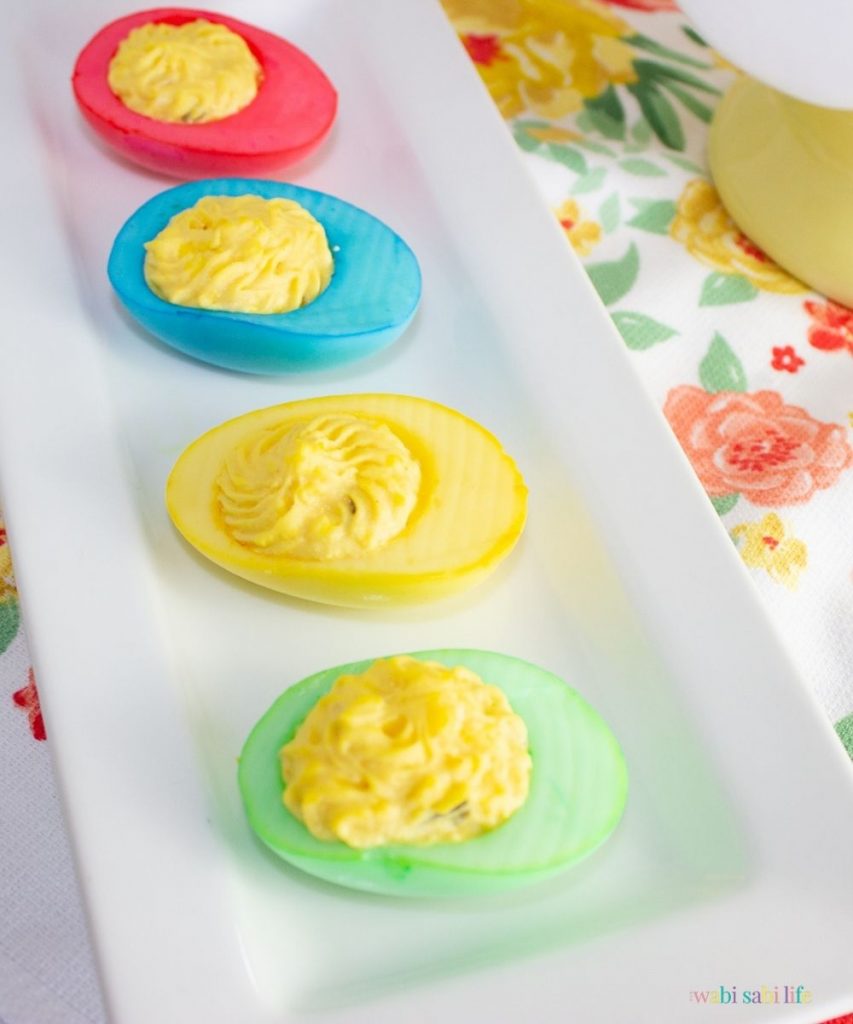 colorful dyed deviled eggs lines d on a white plate