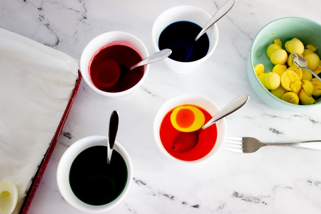 Adding eggs into colored water to color them