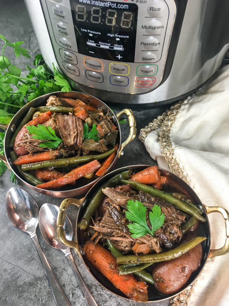 Two bowls of Chuck Roast that has cooked in an Instant Pot with vegetables and topped with parsley