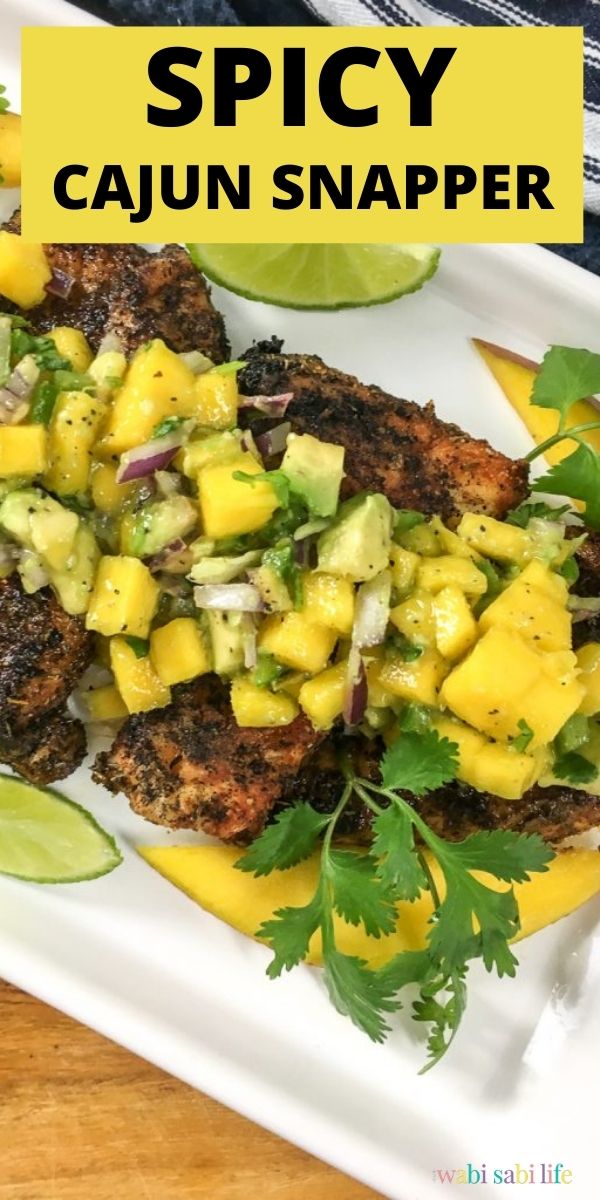 A white tray of spicy Cajun Snapper topped with Mango Salsa