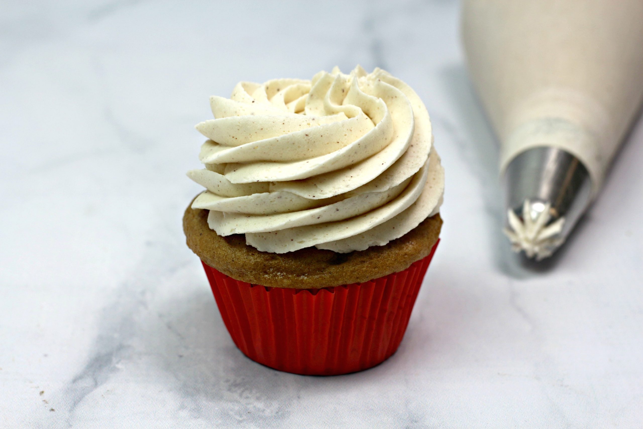 Piping the frosting on baked cupcake.