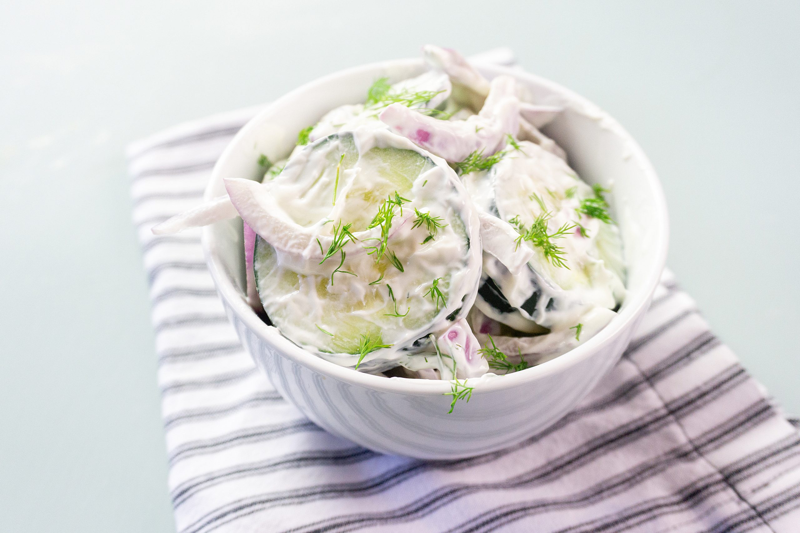 creamy cucumber salad recipe in a white bowl