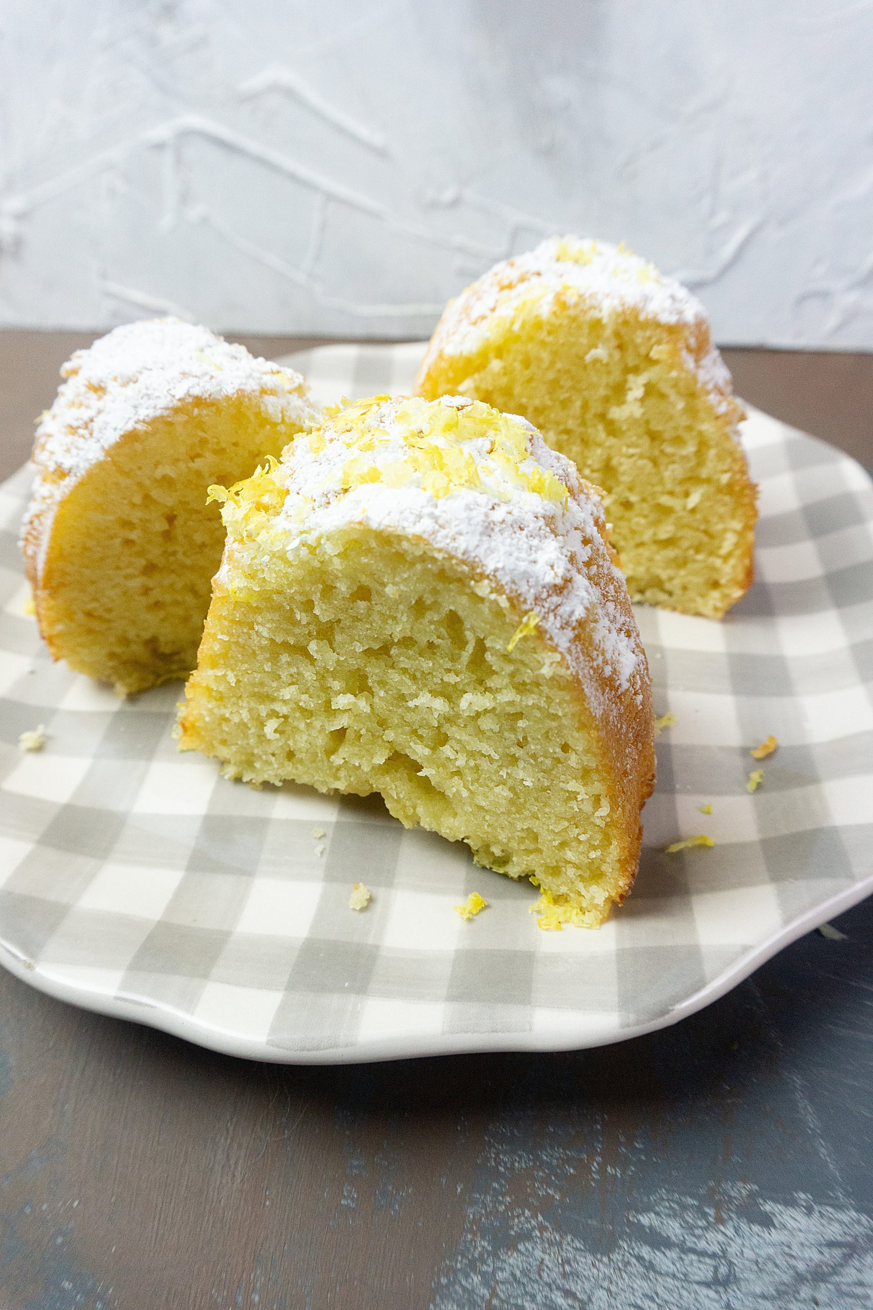 Meyer Lemon Bundt Cake cut into pieces on a serving plate.