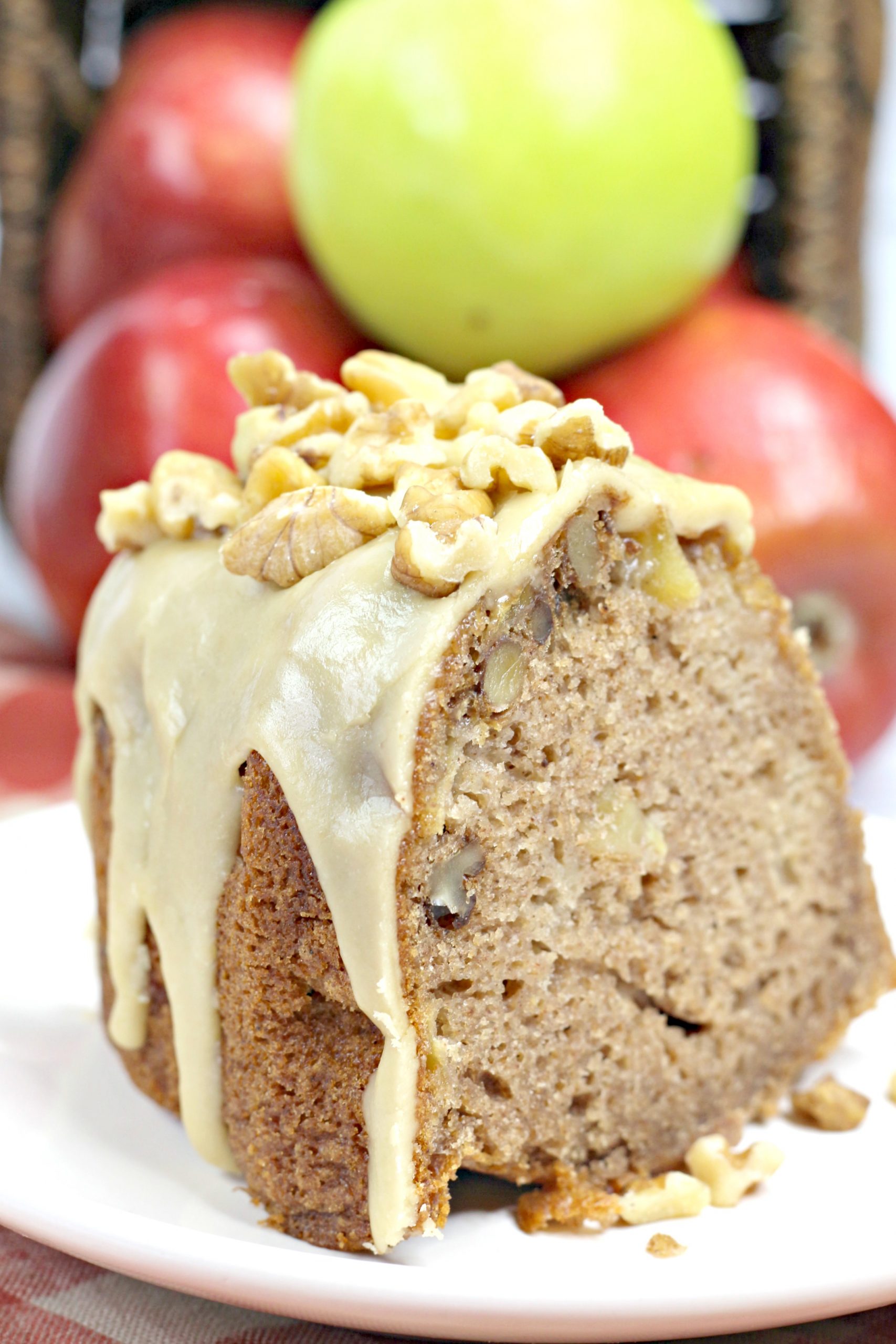 A slice of the caramel apple Bundt with apples behind it.