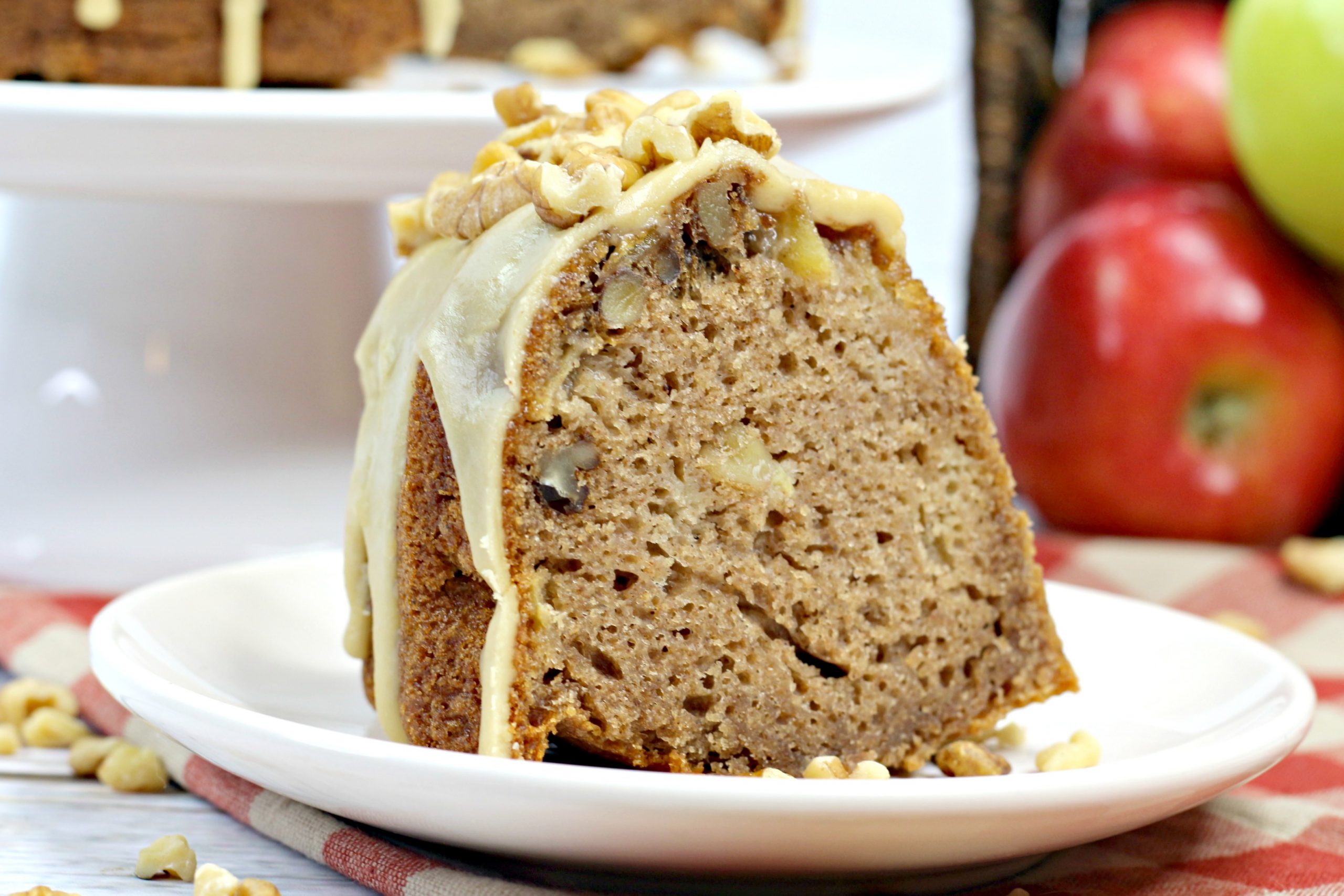 A slice of the caramel apple Bundt cake topped with a glaze and walnuts.