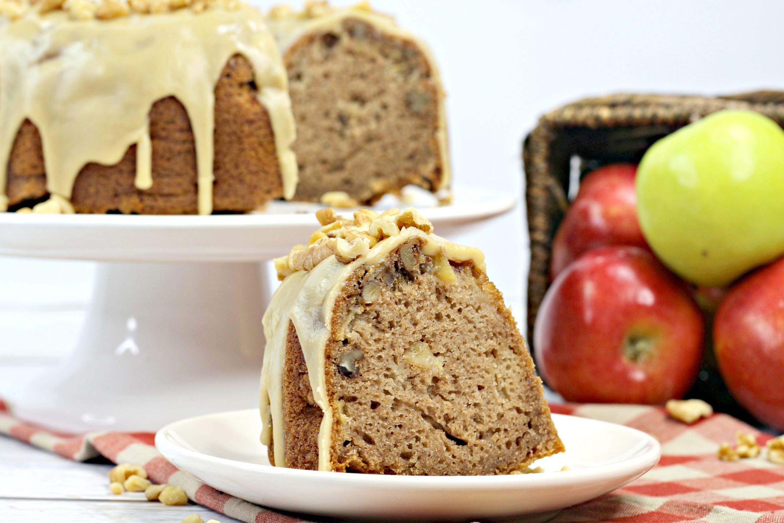 A slice of the caramel apple Bundt with the rest of the cake behind it.