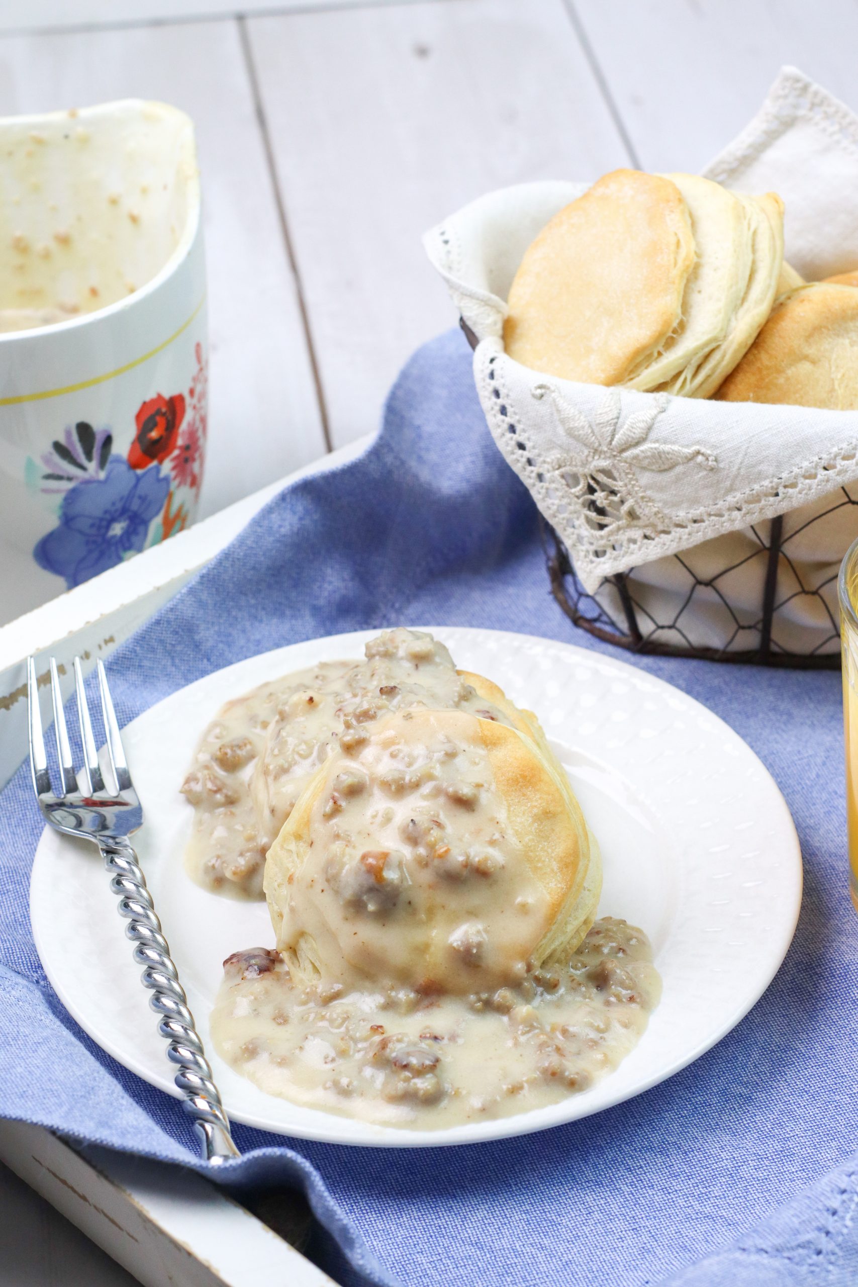 sausage gravy and biscuits on a white plate with a blue background
