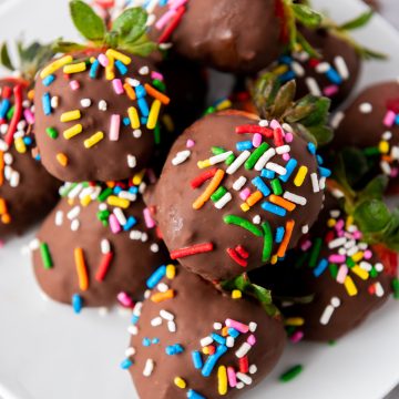 Chocolate covered wine infused strawberries with sprinkles on a white plate